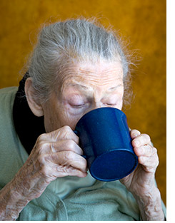 Oudere vrouw drinkt uit beker